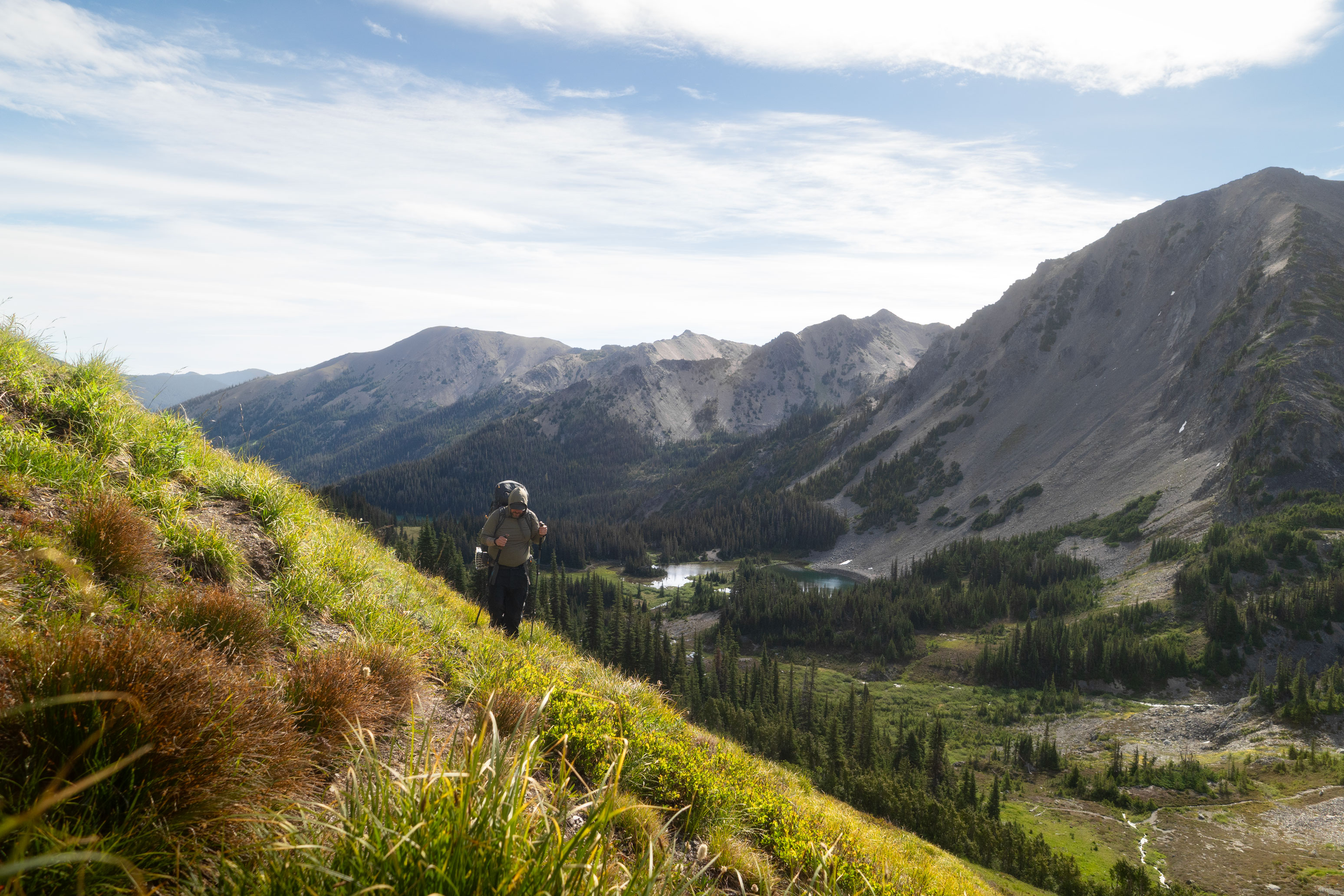 A hiker on a mountain trail overlooking an alpine valley